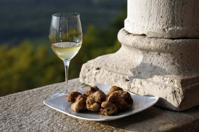 A glass of wine with a plate full of Tuscan black truffles