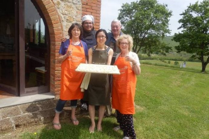 Cooking group in Tuscany presenting their home-made pasta outside in garden.