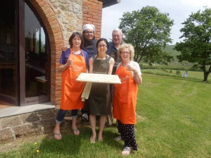 Cooking group in Tuscany presenting their home-made pasta outside in garden.