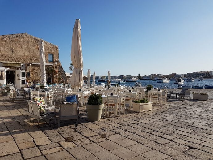 Tables and chairs with a view of Marzamemi harbour