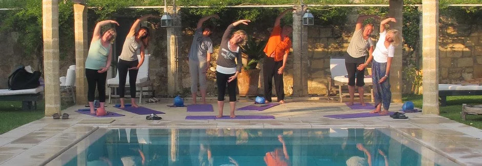 guests doing pilates by pool in sun