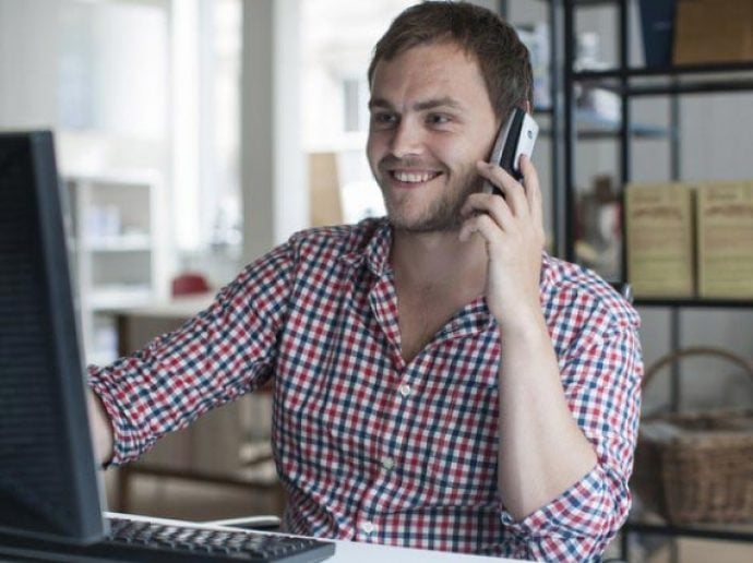 Young man in office smiling and talking on the phone