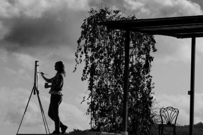 Black and white picture of guest painting Tuscan landscape