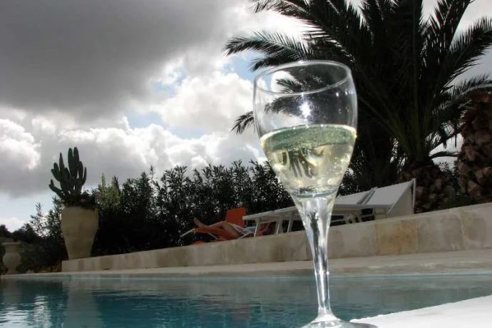 Single traveller relaxing with a glass of Prosecco at the pool