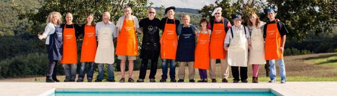 Group of cooking guests wearing aprons and standing arm in arm besides pool