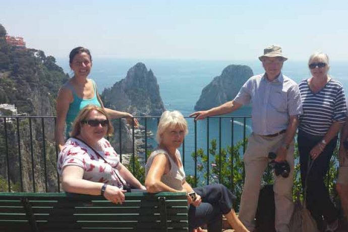 Guests standing on villa's cliffside terrace with stunning view