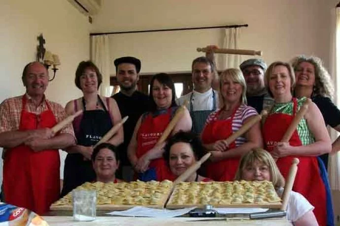 Cookery group with Italian chef showing their freshly made pasta.