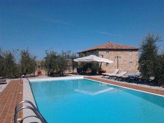 View of villa and outdoor pool from garden. View of holiday villa and outdoor pool in Tuscan Chianti region.