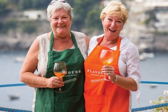 Female guests laughing and enjoying Italian aperitivo in evening sunshine.