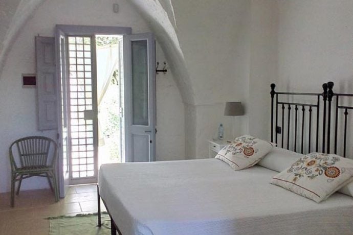 A spacious bedroom flooded with natural light in Puglia.