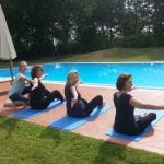 Pilates instructor helping guests by pool