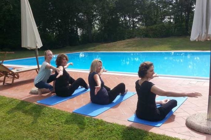 Pilates instructor helping guests by pool