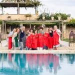 Nine cooking holiday guests laughing in front of swimming pool in our villa in Puglia.