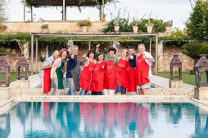 Nine cooking holiday guests laughing in front of swimming pool in our villa in Puglia.