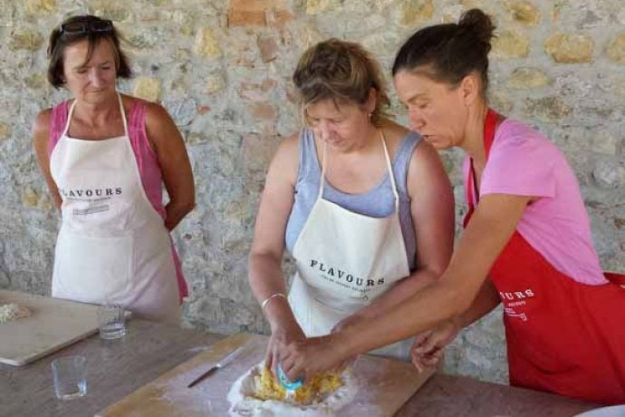 Female chef showing cooking guests how to prepare pasta dough.