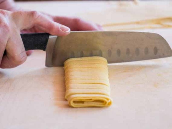 Guest cutting pasta dough into tagliatelle shape.