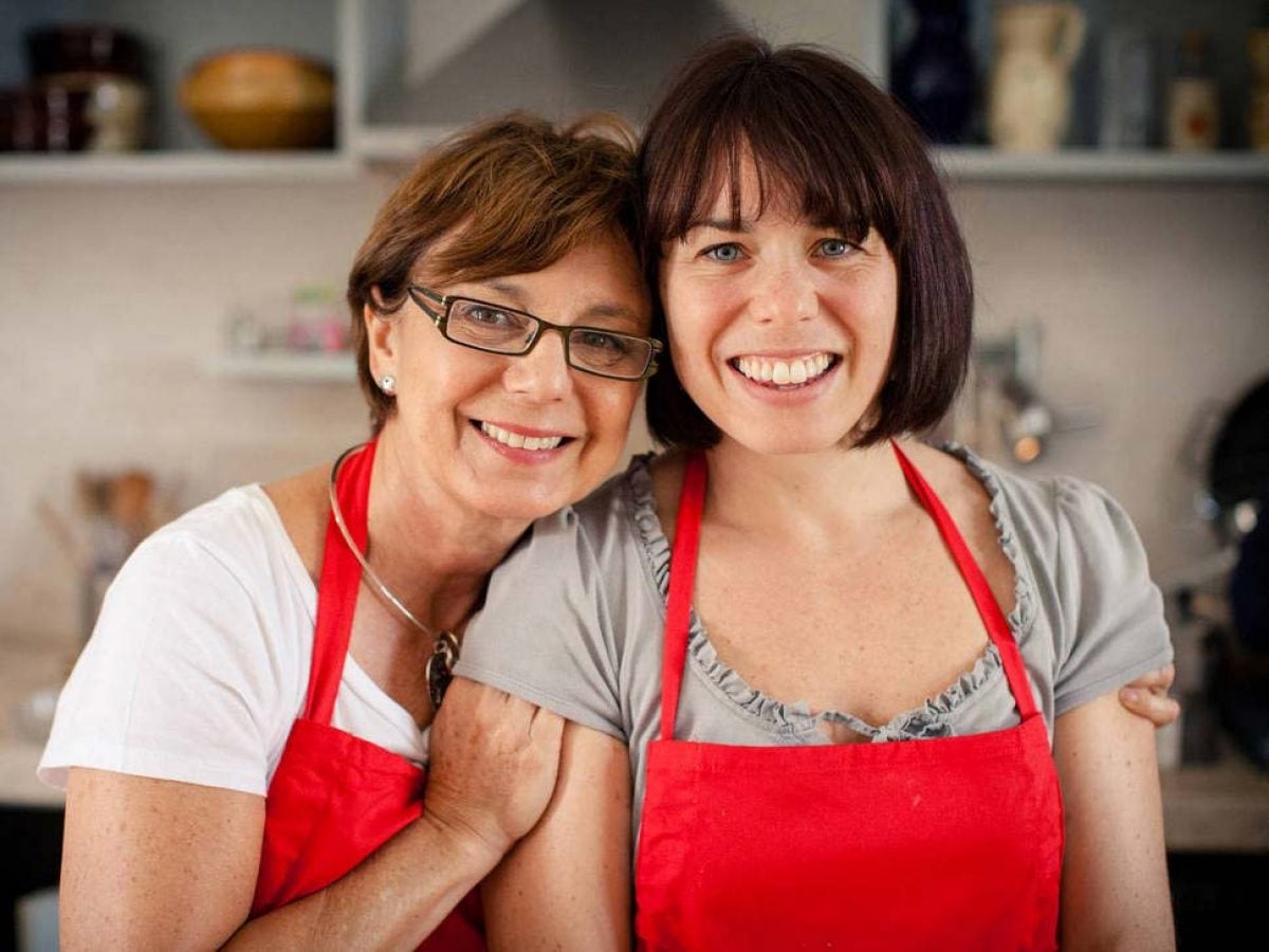 mother and daughter wearing red apron in Italian kitchen