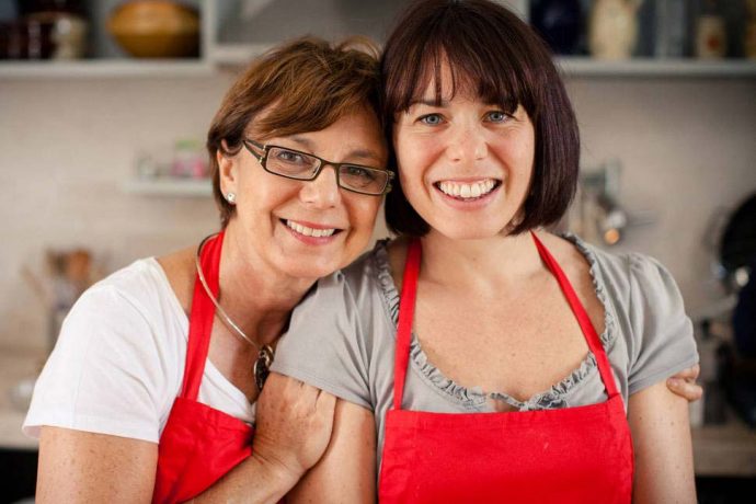 mother and daughter wearing red apron in Italian kitchen