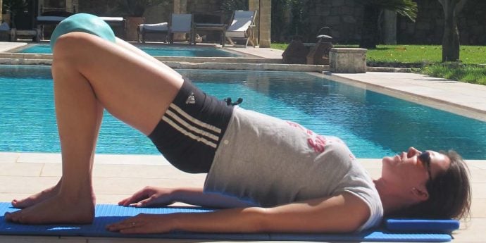 Pilates instructor in spine curl position outside at pool