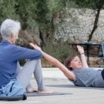 Pilates instructor demonstrating Pilates pose to guests at pool