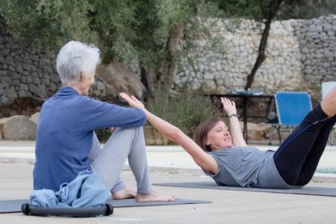 Pilates instructor demonstrating Pilates pose to guests at pool