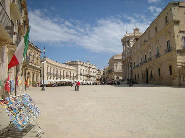 Panorama shot of Piazza del Duomo (Cathedral Square) in Syracuse (Siracusa), Sicily with Italian flag, postcards and restaurants