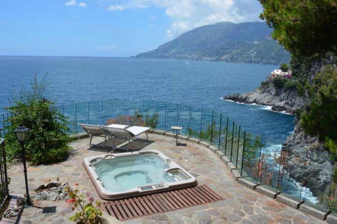 outdoor terrace of private holiday villa with spa and view of sea and cliffs
