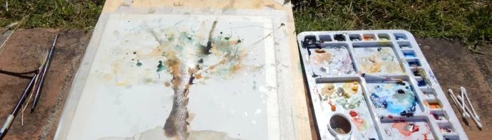 watercolour painting in the making next to a palette of watercolours
