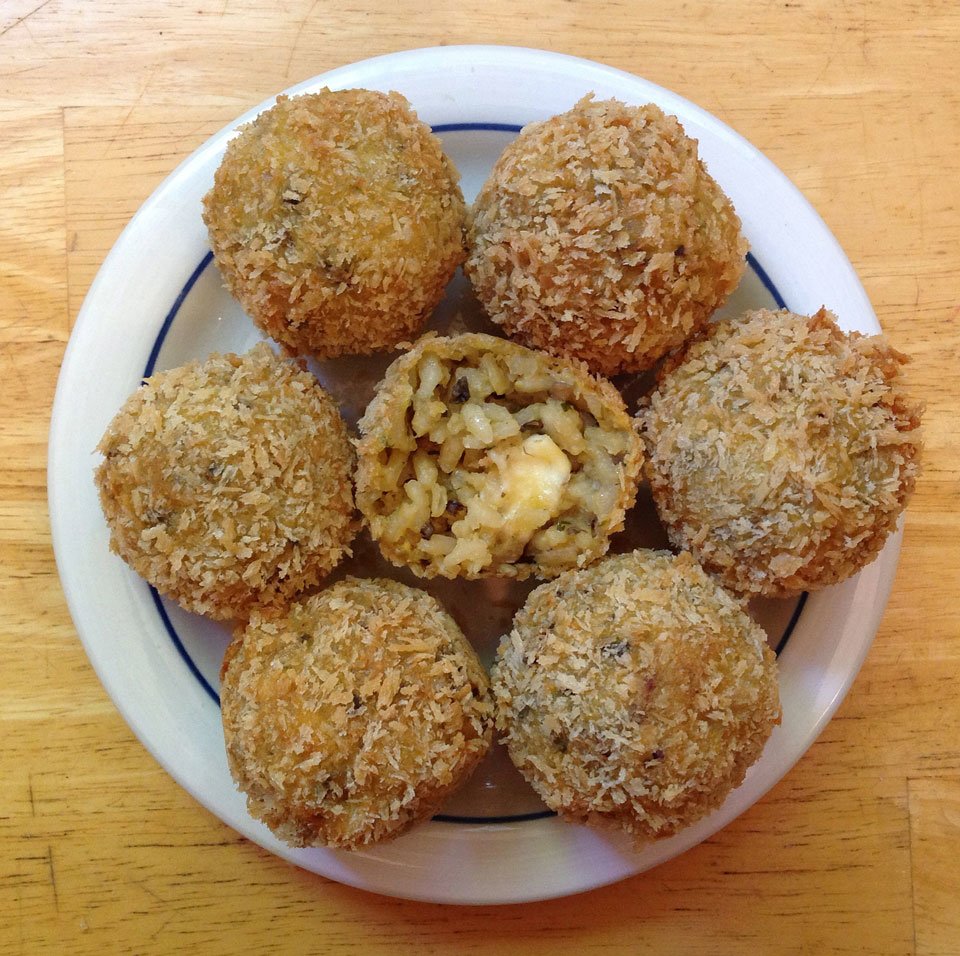 Arancini balls stuffed with Mozzarella on a white plate 