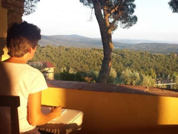 painting student in tuscany sitting on terrace with paper and brush ready to paint