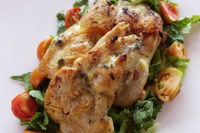 A plate of marinated chicken pieces on a bed of salad leaves