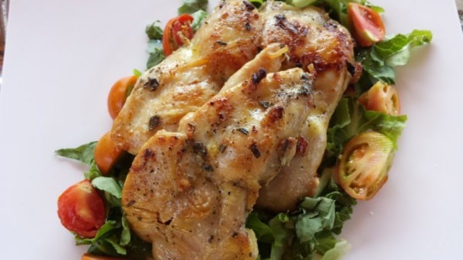 A plate of marinated chicken pieces on a bed of salad leaves