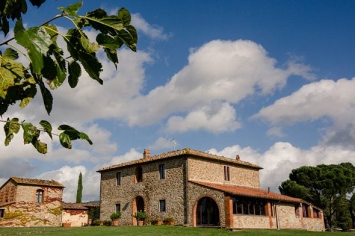 View of rustic Tuscan villa surrounded by cypress trees.