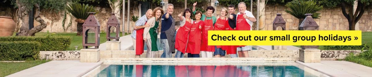 Group of guests smiling and posing in front of pool on holiday