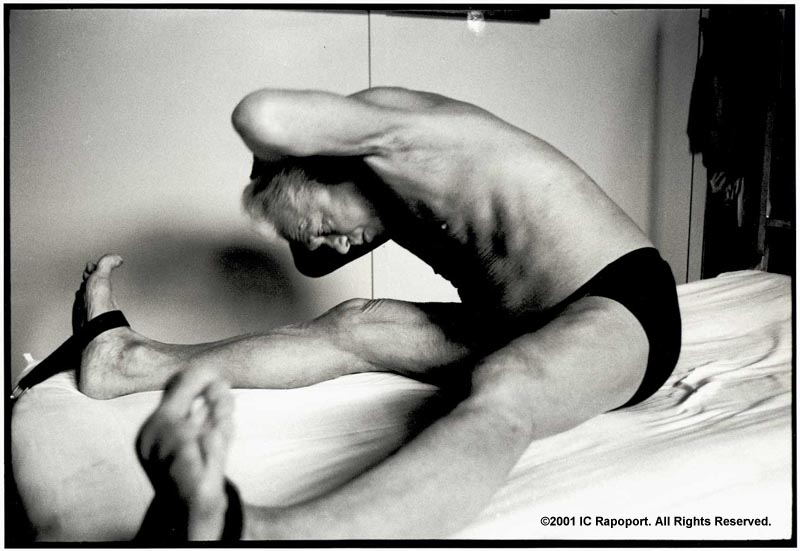 Joseph Pilates on a bed stretching with stretch bands on his feet