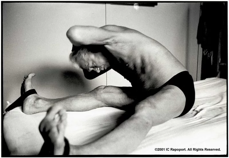 Joseph Pilates on a bed stretching with stretch bands on his feet