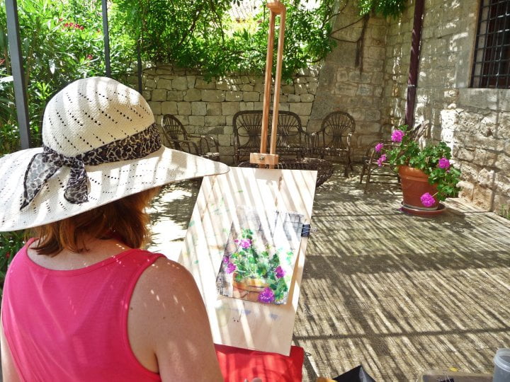 Woman painting flowering pot plant in the sun