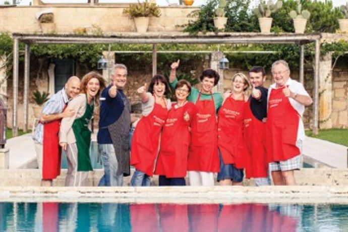 group of guests wearing aprons and laughing in front of the swimming pool