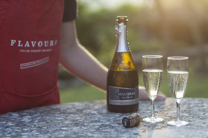 Two glasses and a bottle of prosecco being served by Flavours host