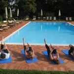 Group of Flavours guests doing Pilates beside the pool in Italy