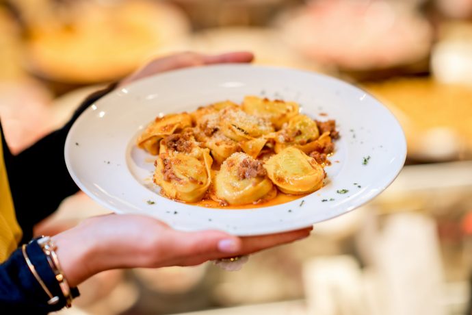 Lady holding bowl of tortellini bolognese