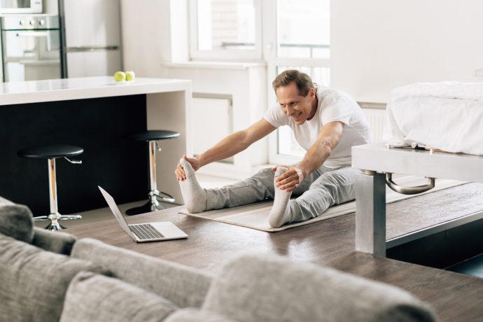 Man Practising Pilates in front of Laptop in his Living Room