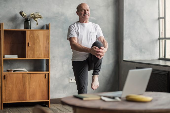 Man Practising Pilates in front of Laptop in his Living Room