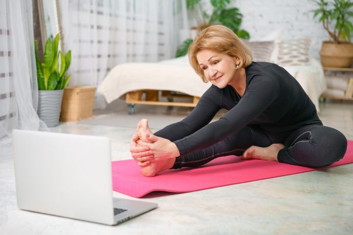 Woman Practising Pilates in front of Laptop in her Living Room