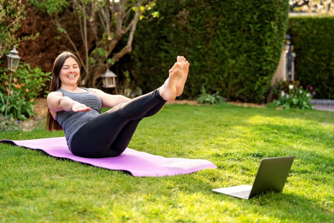 Woman Practising Pilates in front of Laptop in her Garden