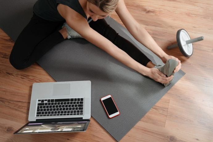 Woman Practising Pilates in front of Laptop in her Living Room
