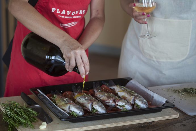 Flavours chef drizzling oil over a tray of prepared fish