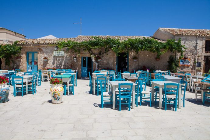 Sunny tables and chairs outside a restaurant in Sicily