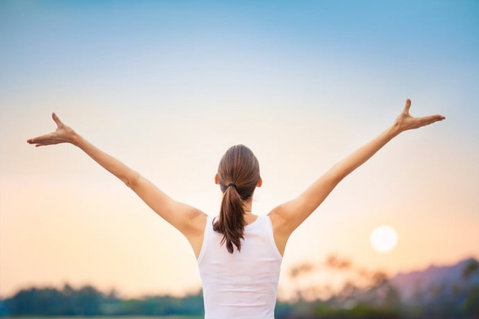 Woman wirh arms in the air after well being class