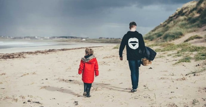 child and adult walking along the beach